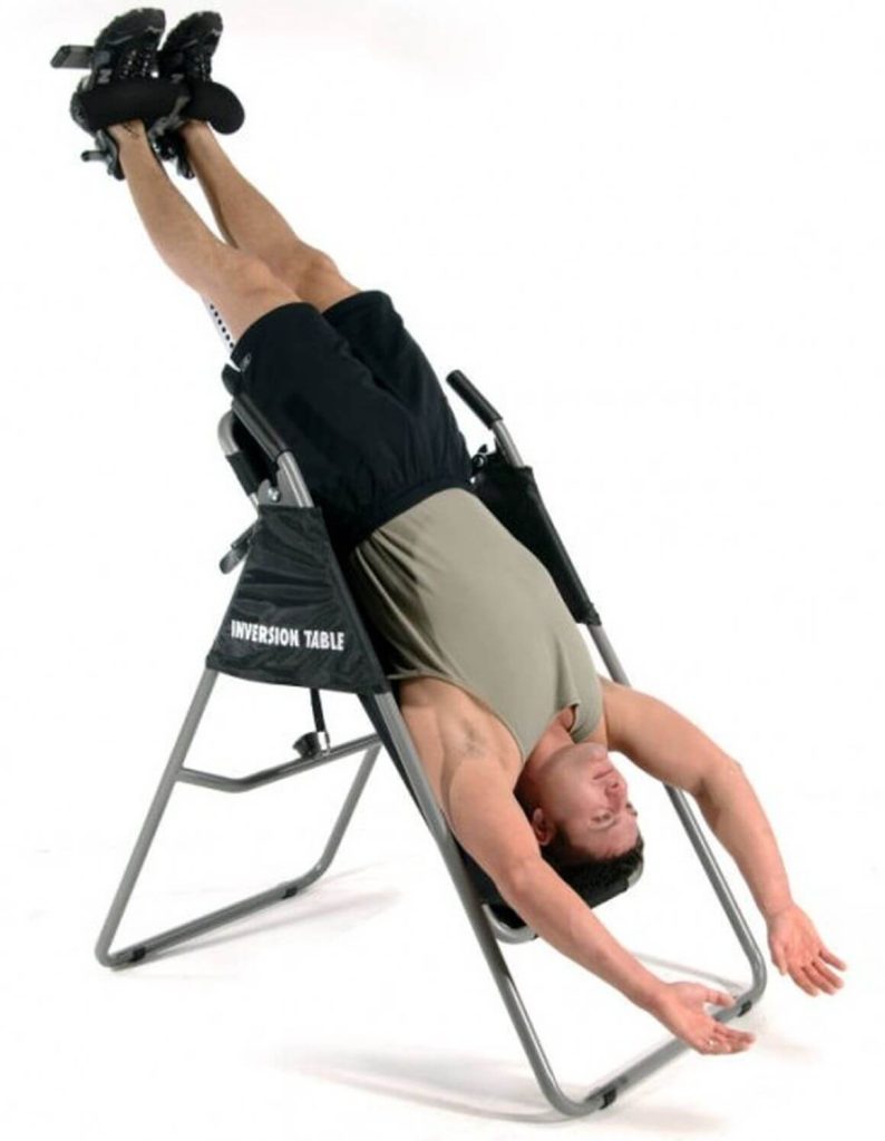 A man hanging on an inversion table